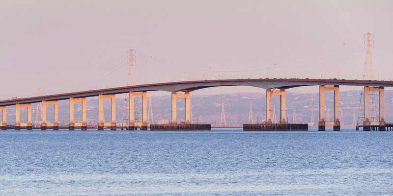 The San Mateo bridge over water with a pink sky