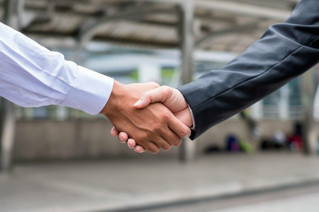 Business professionals shaking hands to establish a digital marketing partnership for credit union growth.